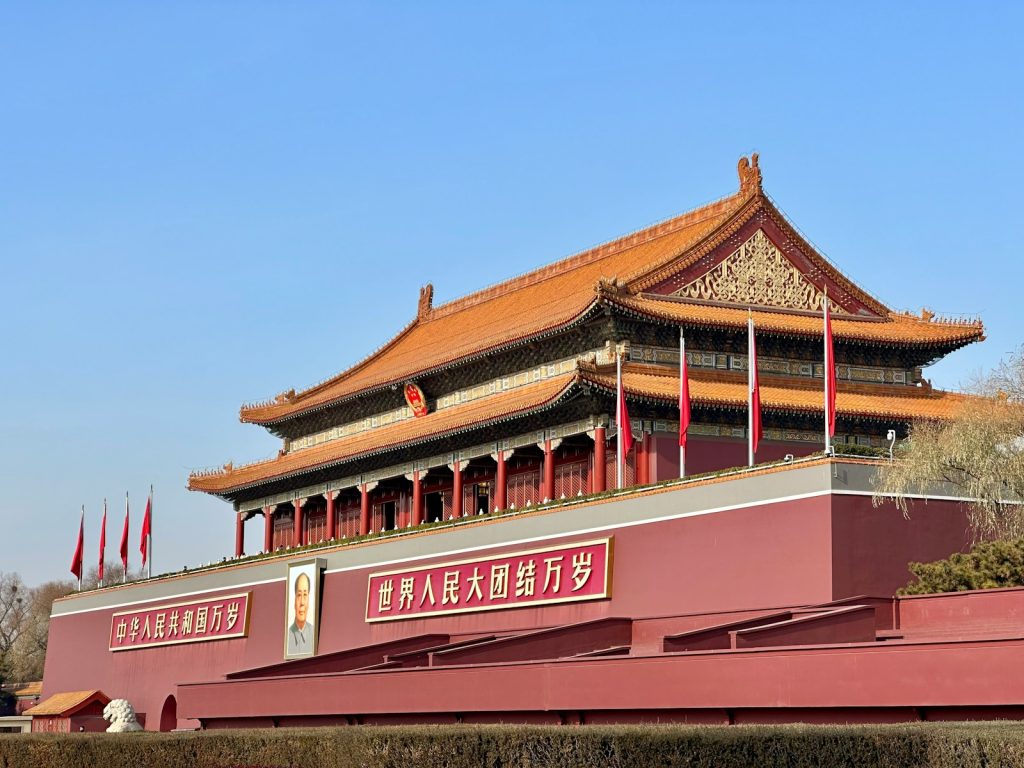 a tall building with a red roof next to a wall